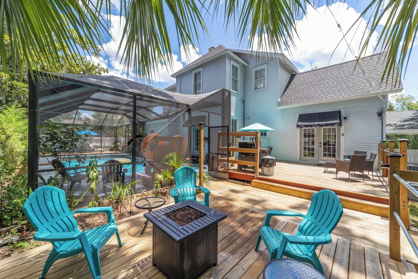 Une terrasse extérieure couverte avec une piscine, des chaises et un espace barbecue.