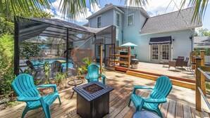 Um deck coberto ao ar livre com piscina, cadeiras e espaço para churrasco.