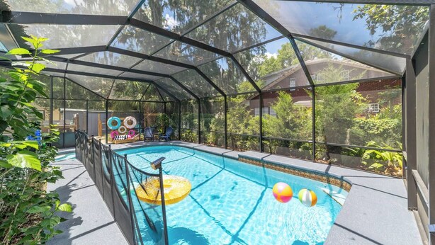 Piscina coberta com cerca de proteção, espreguiçadeiras e boias infláveis.