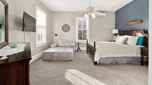 Quarto com cama, cadeira, escrivaninha, espelho e ventilador de teto.