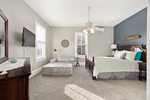 A bedroom with a bed, a chair, a desk, a mirror, and a ceiling fan. - Historic downtown 2/1 upper floor suite w/pool (Ocala)