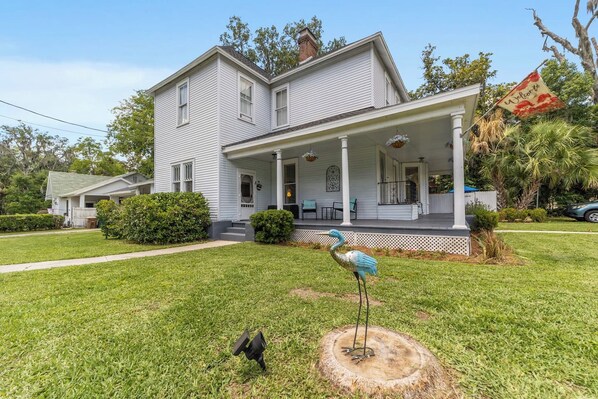 A two-story house with a porch and a bird sculpture.
