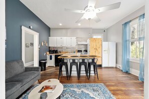 A modern kitchen with white cabinets, a wooden island, and black bar stools.