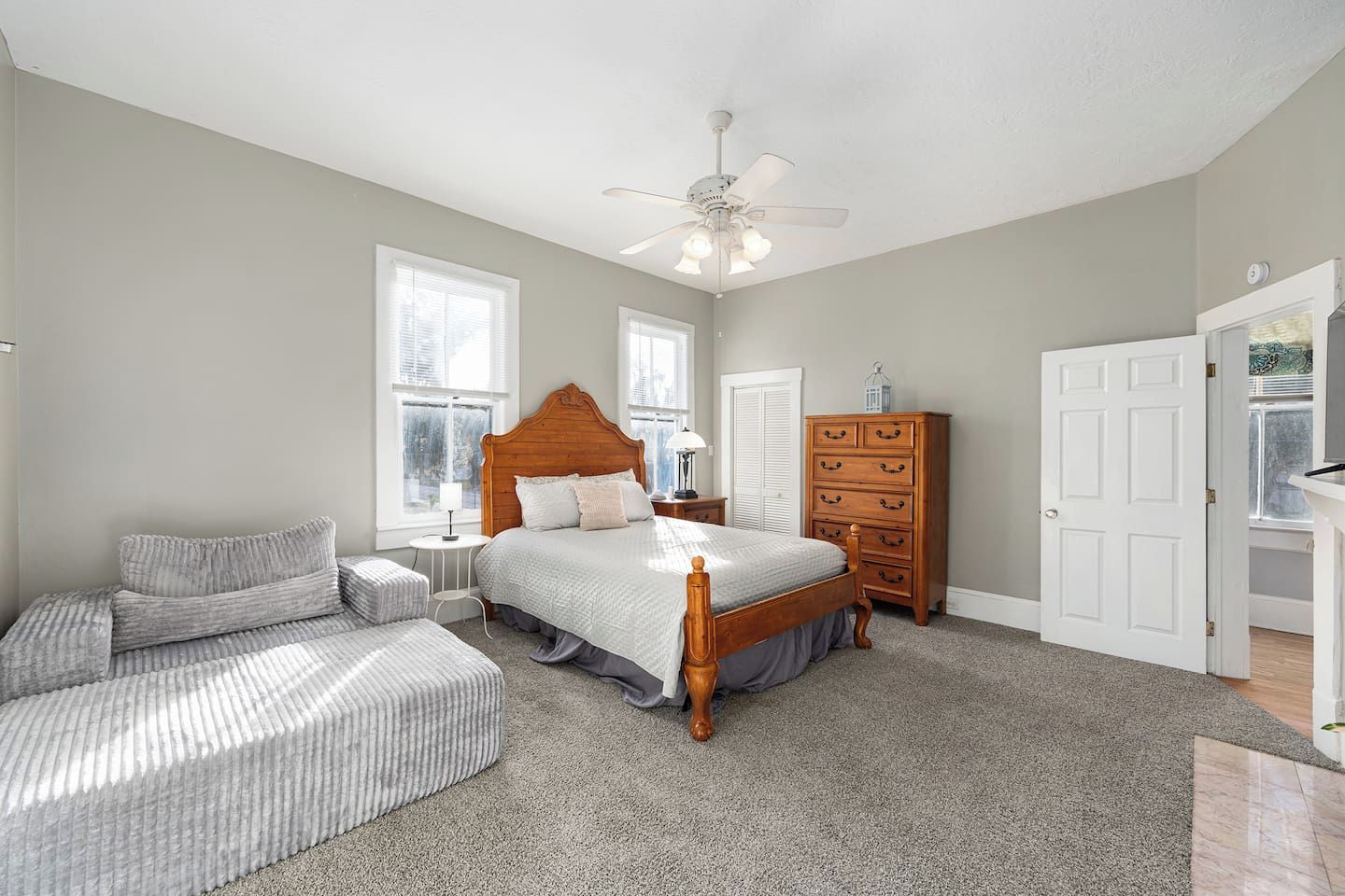 A bedroom with a bed, a dresser, a nightstand, a chair, and a ceiling fan.