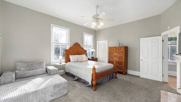 A bedroom with a bed, a dresser, a nightstand, a chair, and a ceiling fan.