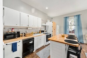 A compact kitchen with white cabinets, a microwave, a coffee maker, and a stove.