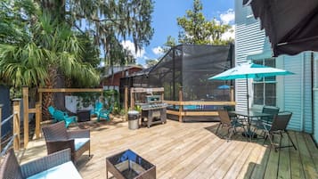 A wooden deck with outdoor furniture, a grill, and a covered seating area.