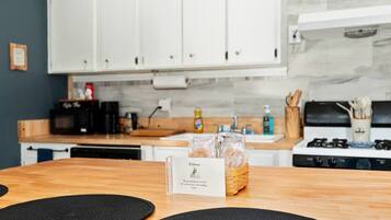 A kitchen with white cabinets, a wooden countertop, a stove, and a welcome card on the table.