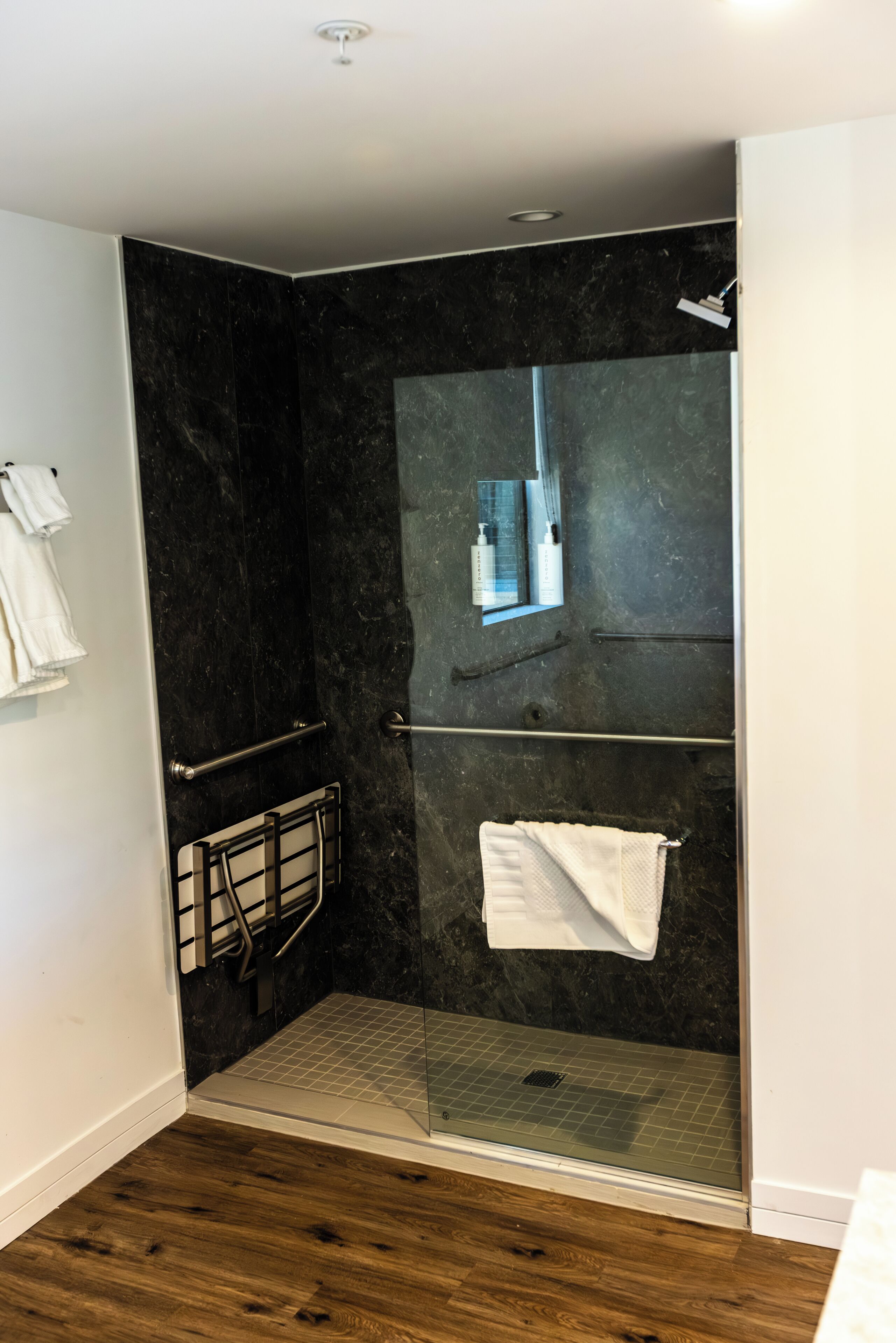A modern bathroom with a glass shower enclosure, a towel rack, and a built-in mirror.