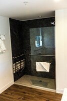 Un baño moderno con cabina de ducha de vidrio, un perchero y un espejo integrado.