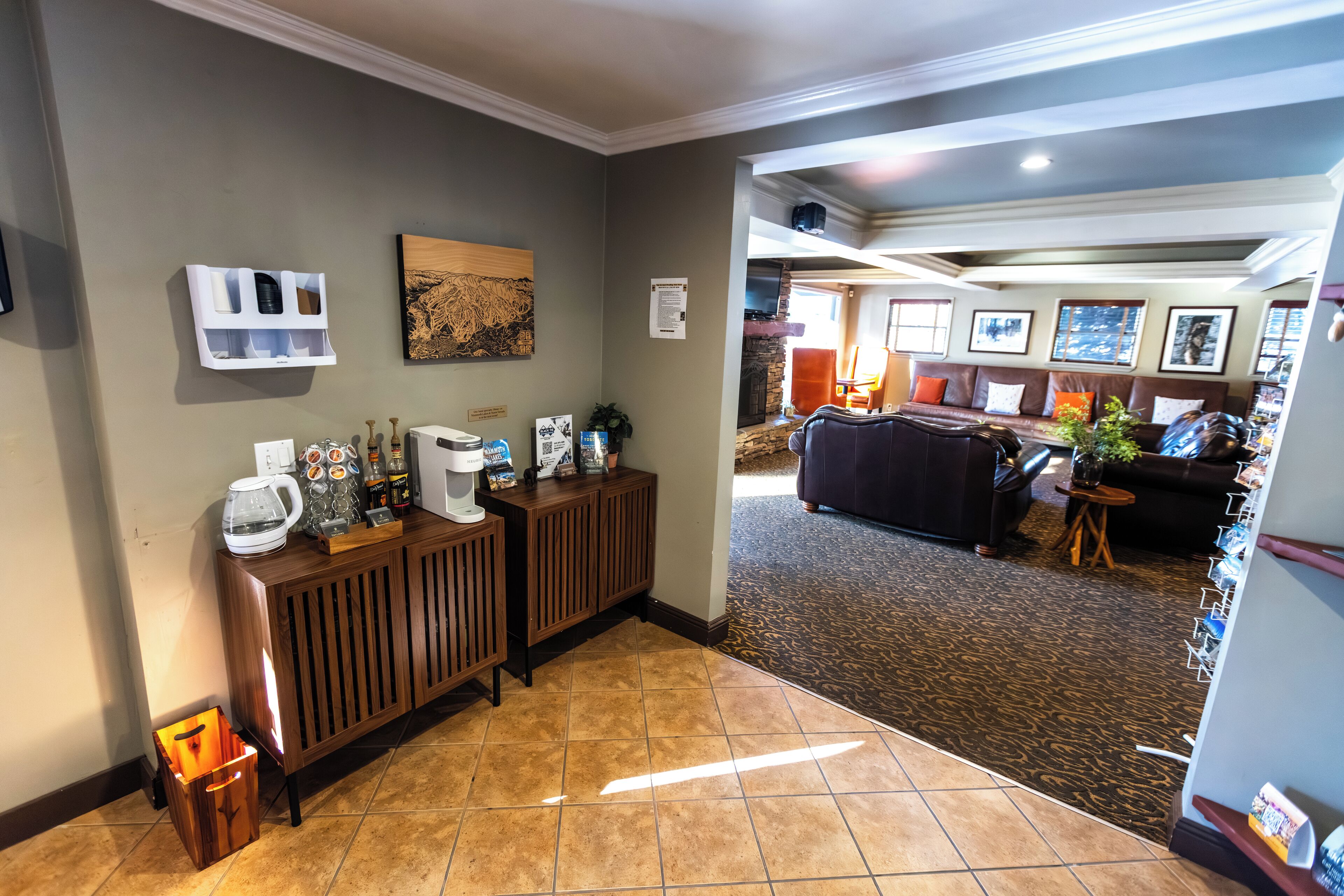 Un hall d’hôtel comprenant un comptoir d’accueil, un coin café, une cheminée et un espace détente avec un canapé et des fauteuils.