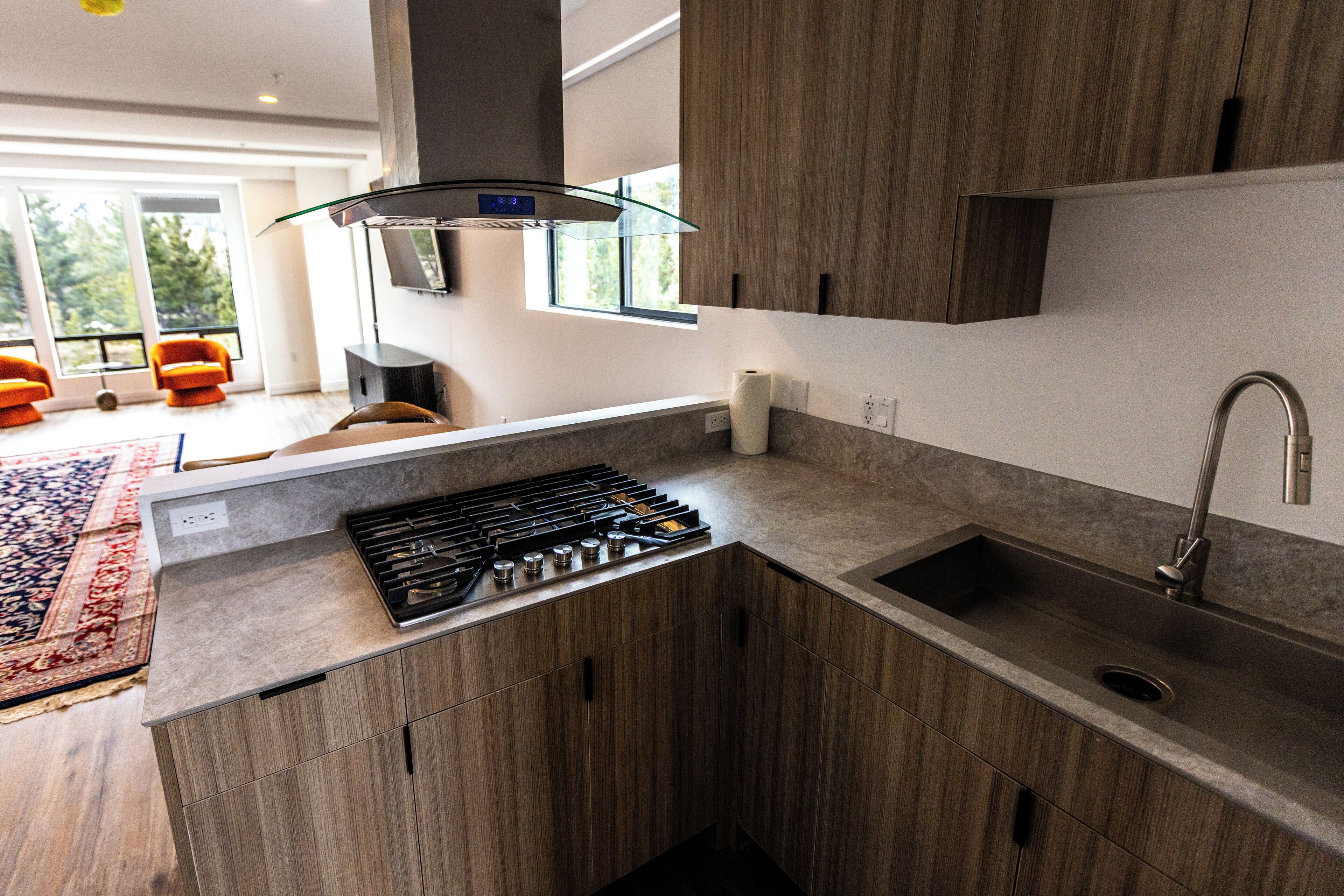 Una cocina moderna con estufa a gas integrada, pileta de acero inoxidable y armarios de madera.