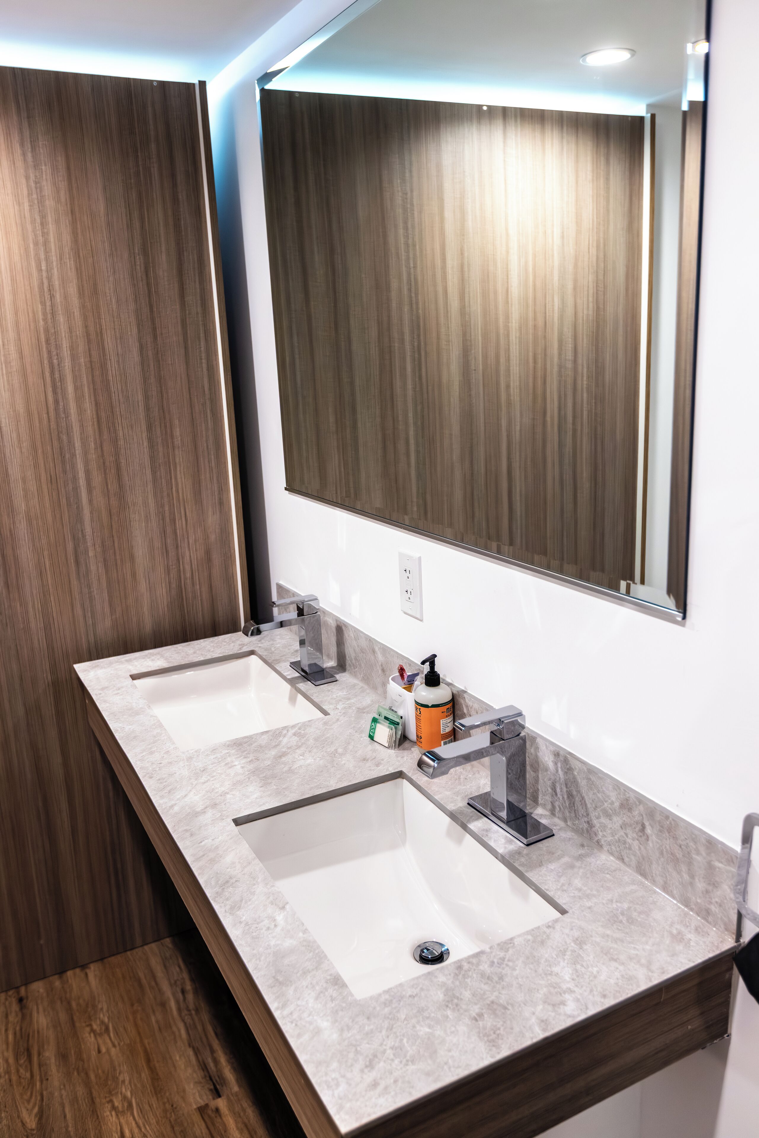 Un baño moderno con dos lavamanos, un espejo grande y paneles de madera.
