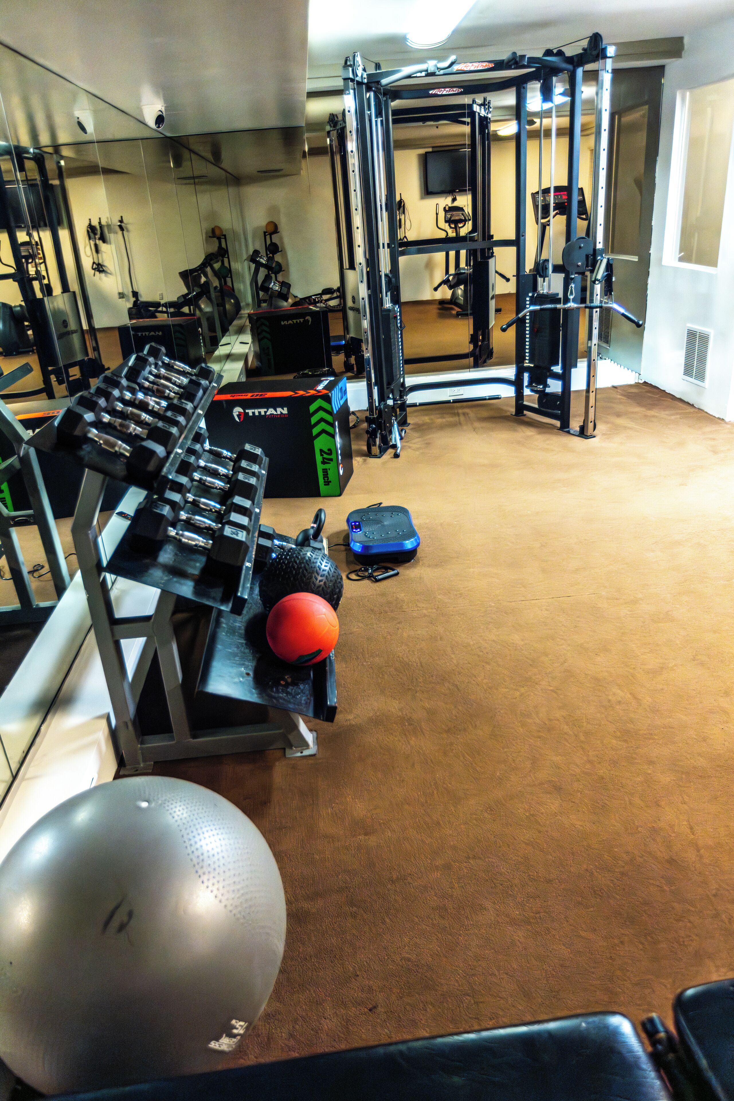 A gym with weightlifting equipment, exercise balls, and a mirrored wall.