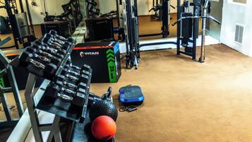 A gym with weightlifting equipment, exercise balls, and a mirrored wall.