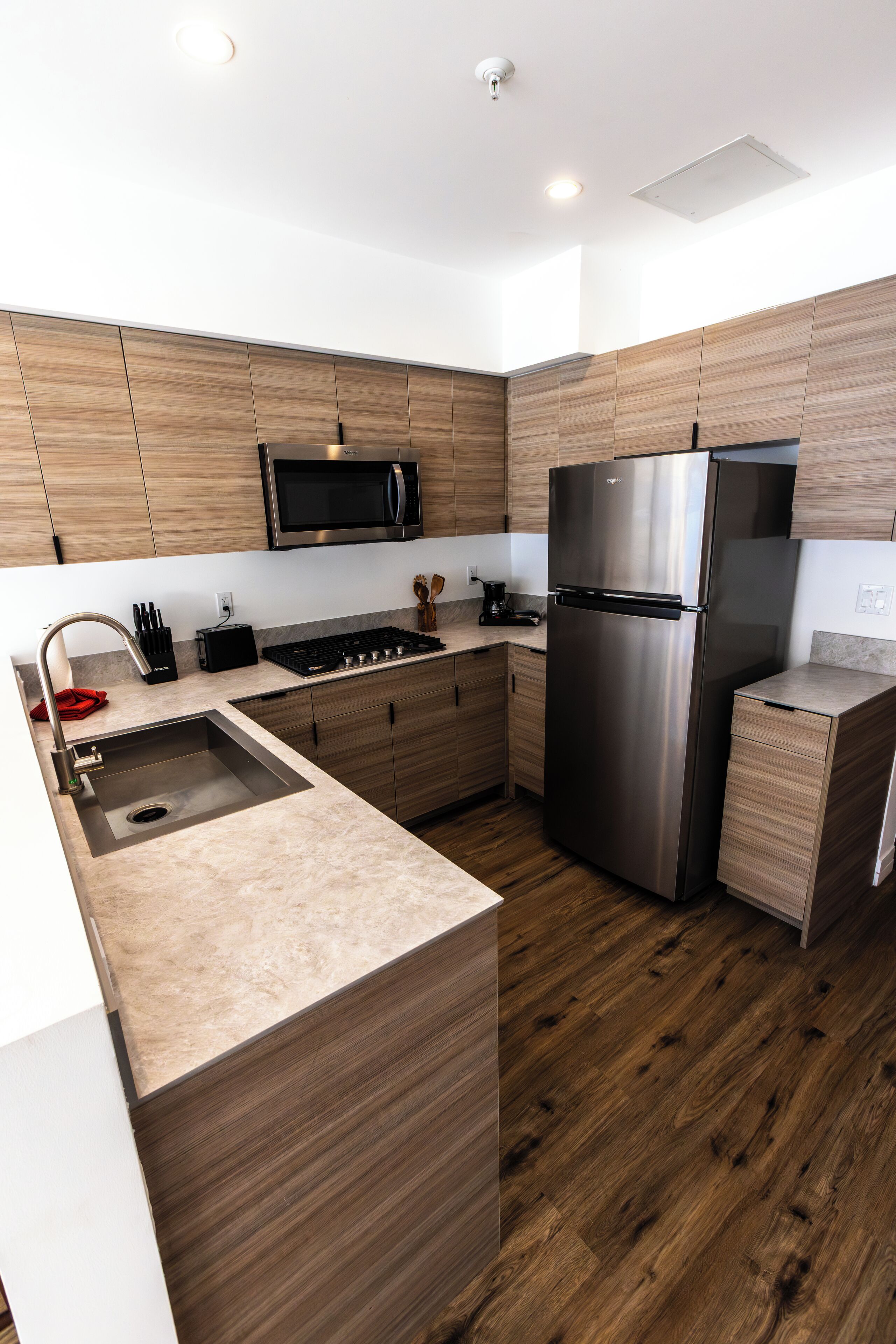 A modern kitchen with wooden cabinets, stainless steel appliances, and a marble countertop.