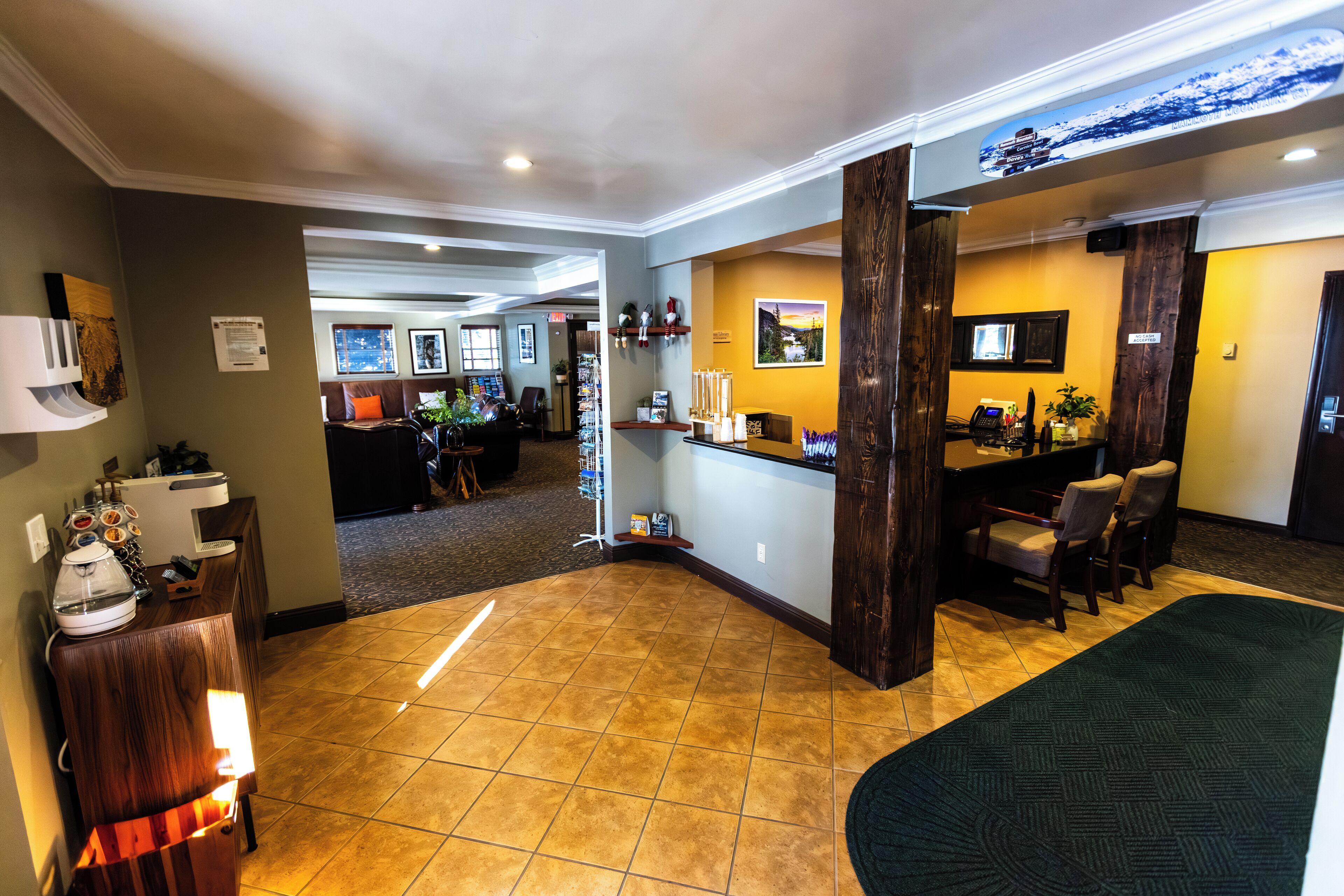 A hotel lobby with a reception desk, seating area, and a view of the dining area.