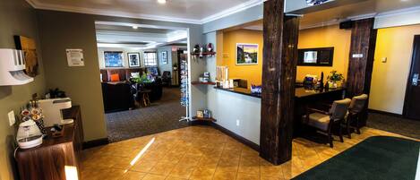 A hotel lobby with a reception desk, seating area, and a view of the dining area.