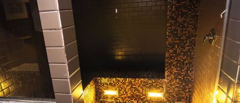 A tiled shower area with a mosaic floor and a glass door.