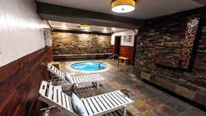 A spa area with a hot tub, wooden benches, and a stone wall.