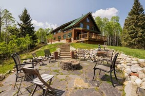 Eine Blockhütte mit einer Steinterrasse und einer Sitzgelegenheit im Freien.