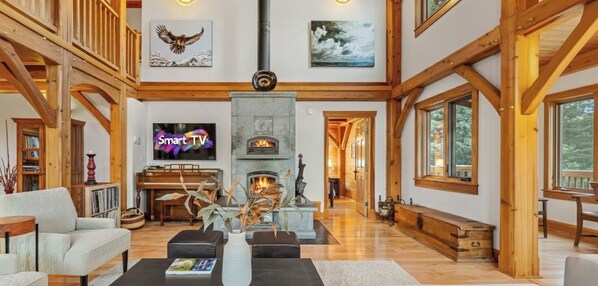 Ein geräumiges Wohnzimmer mit Kamin, einem Klavier und einem Fernseher mit der Aufschrift "Smart TV".