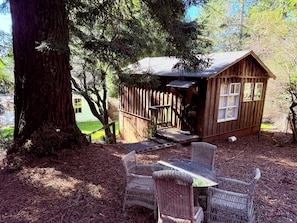 Une cabane en bois rustique, dotĂ©e dâun porche et entourĂ©e dâarbres.