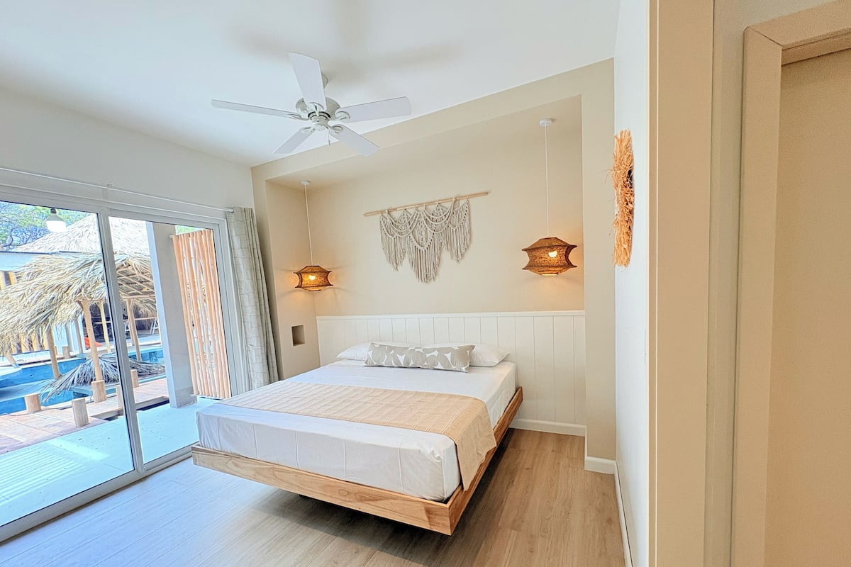 A modern bedroom with a large bed, a ceiling fan, and two wall-mounted lights.