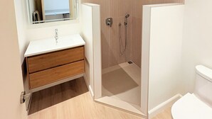 Une salle de bain moderne avec un meuble-lavabo blanc, une cabine de douche et des toilettes.