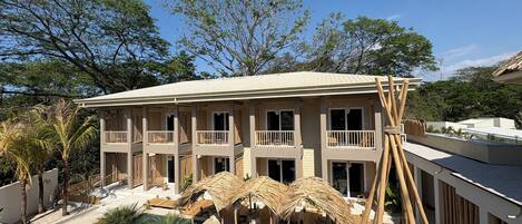 A hotel with a pool, outdoor seating, and a large tree in the background.