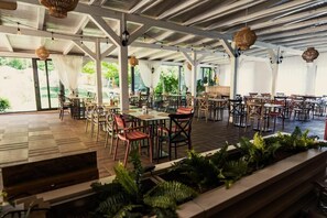 Un espace de restauration intérieur avec des tables et des chaises, de grandes fenêtres et des luminaires suspendus.