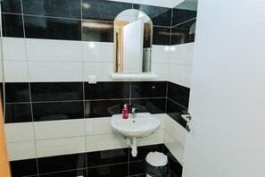 Une salle de bain avec un lavabo blanc, un miroir et des carreaux noirs et blancs.