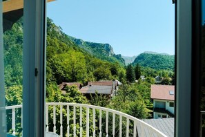A balcony with a view of a mountainous landscape and residential buildings.