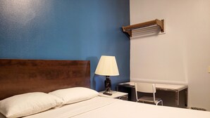 A hotel room with a bed, a desk, a chair, a lamp, and an air conditioning unit. - AVAION HOTEL LAX-SoFi Stadium (Inglewood)