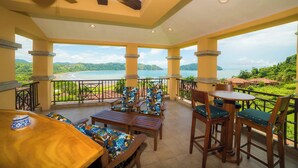 Un balcón con mobiliario de madera y vista a un lago y montañas.