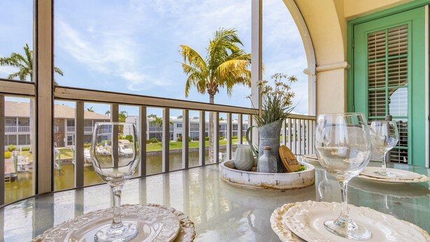 Ein Balkon mit Glastisch, zwei Weingläsern und einer dekorativen Tischmitte.