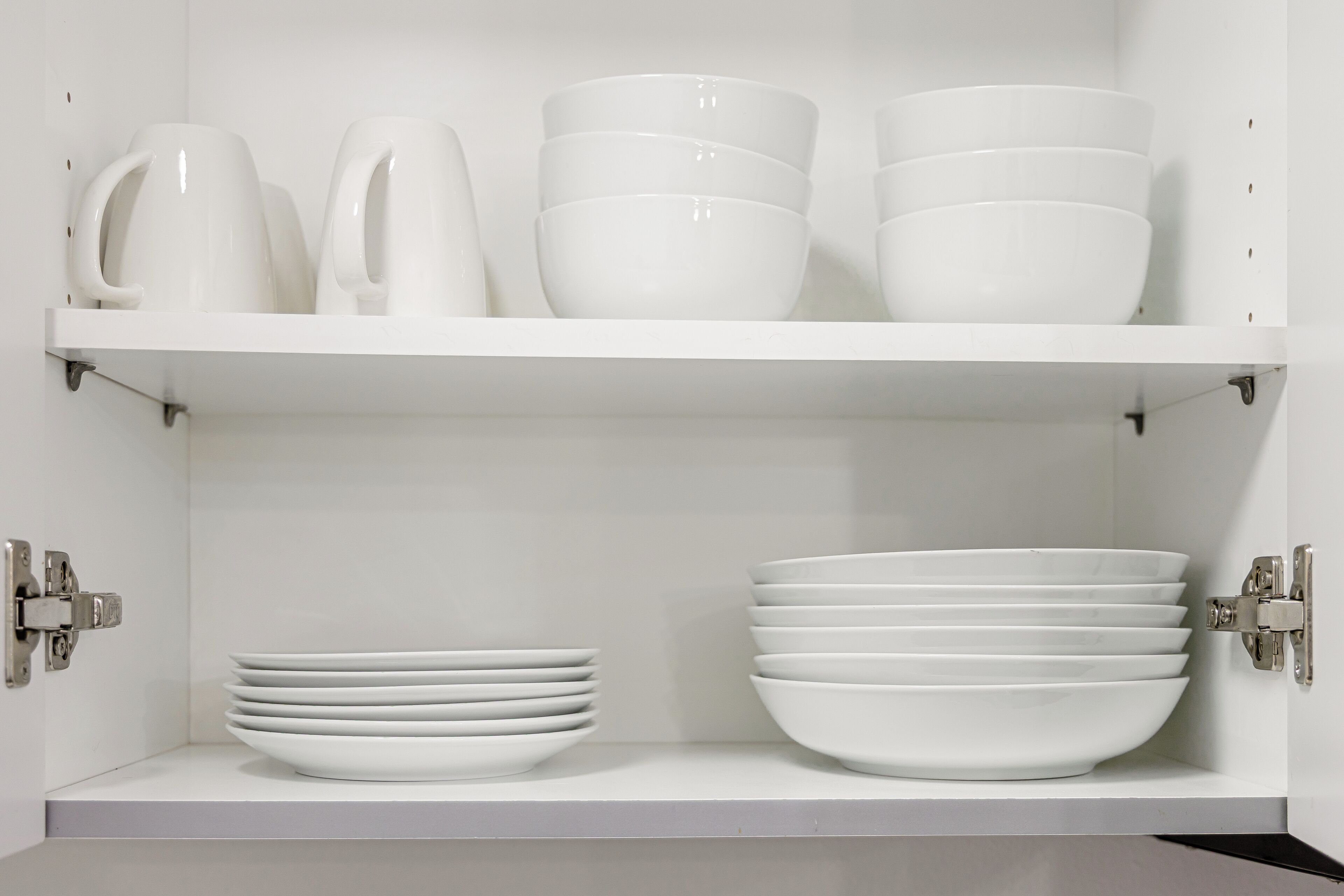 Una estantería blanca con cuencos y platos blancos.