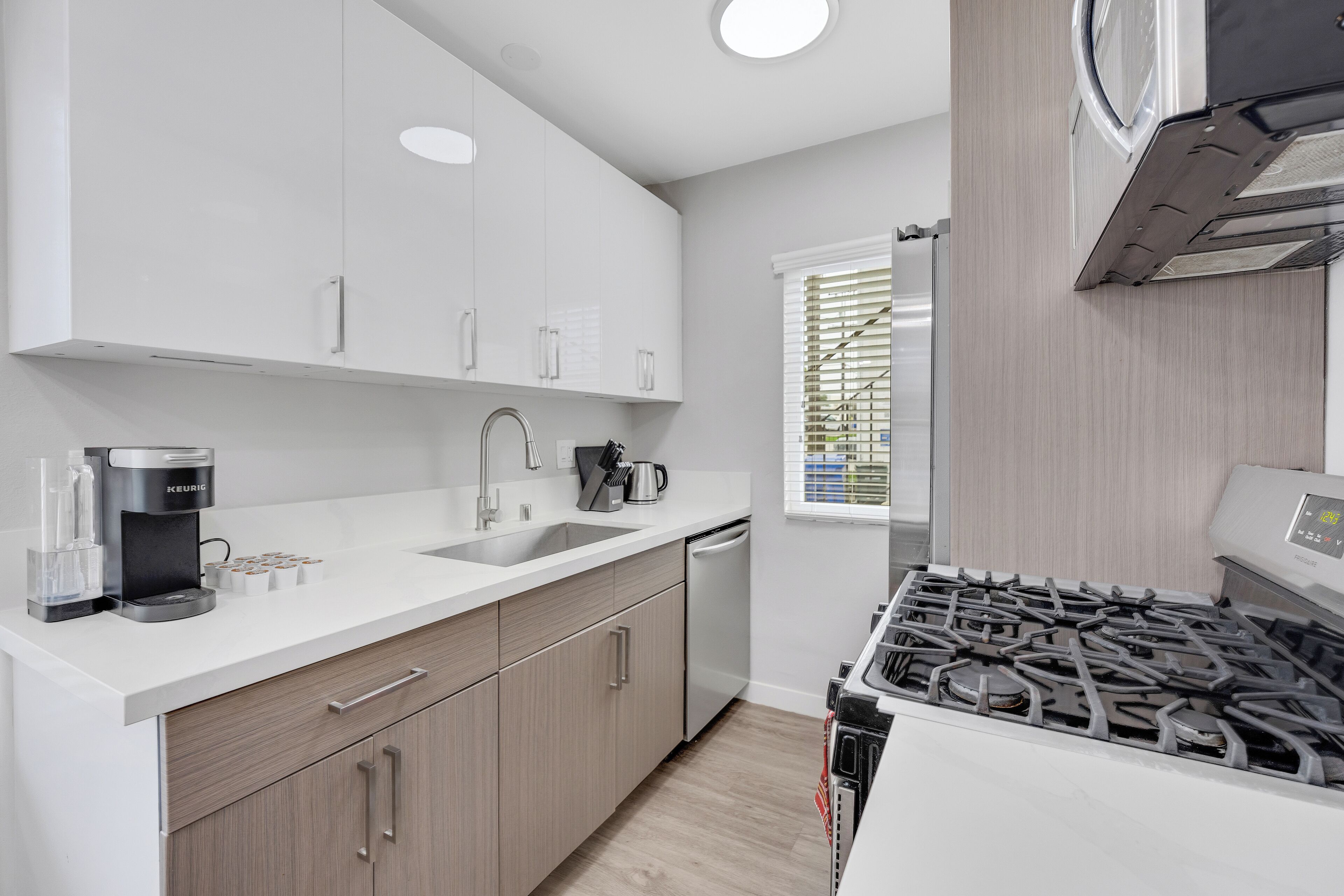 A modern kitchen with white cabinetry, a stainless steel range, and a dishwasher.
