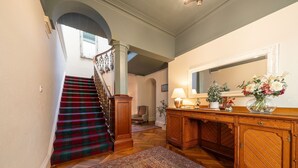 Eine Treppe mit kariertem Teppich, ein Holzschrank mit Spiegel und ein gemustertes Läufchen.