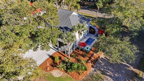 An aerial view of a house with a swimming pool, surrounded by trees and a well-maintained garden.