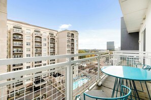 A balcony with a pool, white railings, and a view of surrounding buildings.