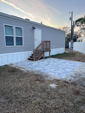 A single-story mobile home with a wooden deck and a small porch. - Pet Friendly Cozy 2-bedroom manufactured home with accessible feature's (North Fort Myers)