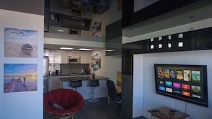 Una cocina moderna con comedor, un televisor mostrando servicios de streaming y obras de arte en las paredes.