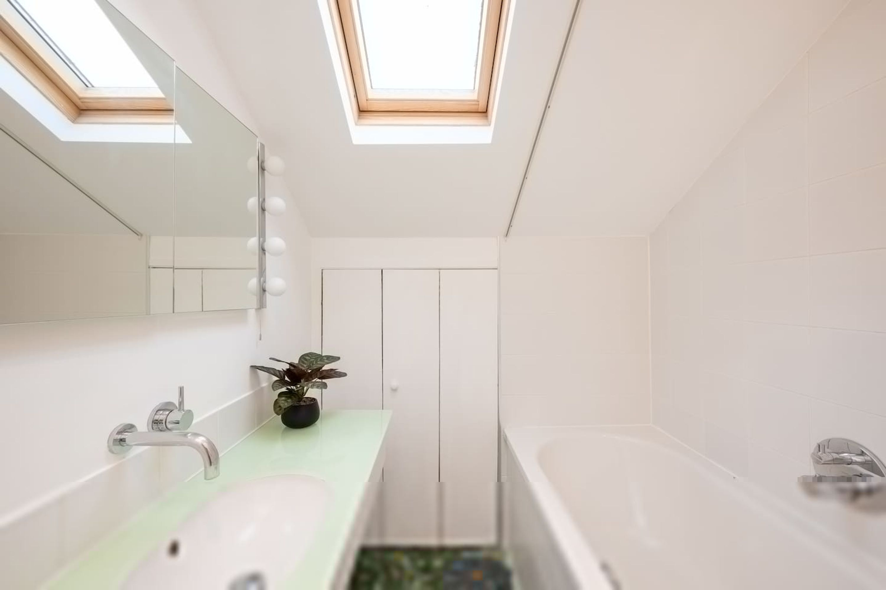 Un bagno moderno con lucernari, un lavandino, uno specchio e una vasca da bagno.