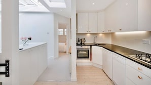 A modern kitchen with white cabinets, a black countertop, and a skylight. - Luxury Penthouse in Maida Vale With Fast Wi-fi (London)