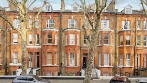 A row of red brick townhouses with bay windows and a central staircase. - Luxury Penthouse in Maida Vale With Fast Wi-fi (London)
