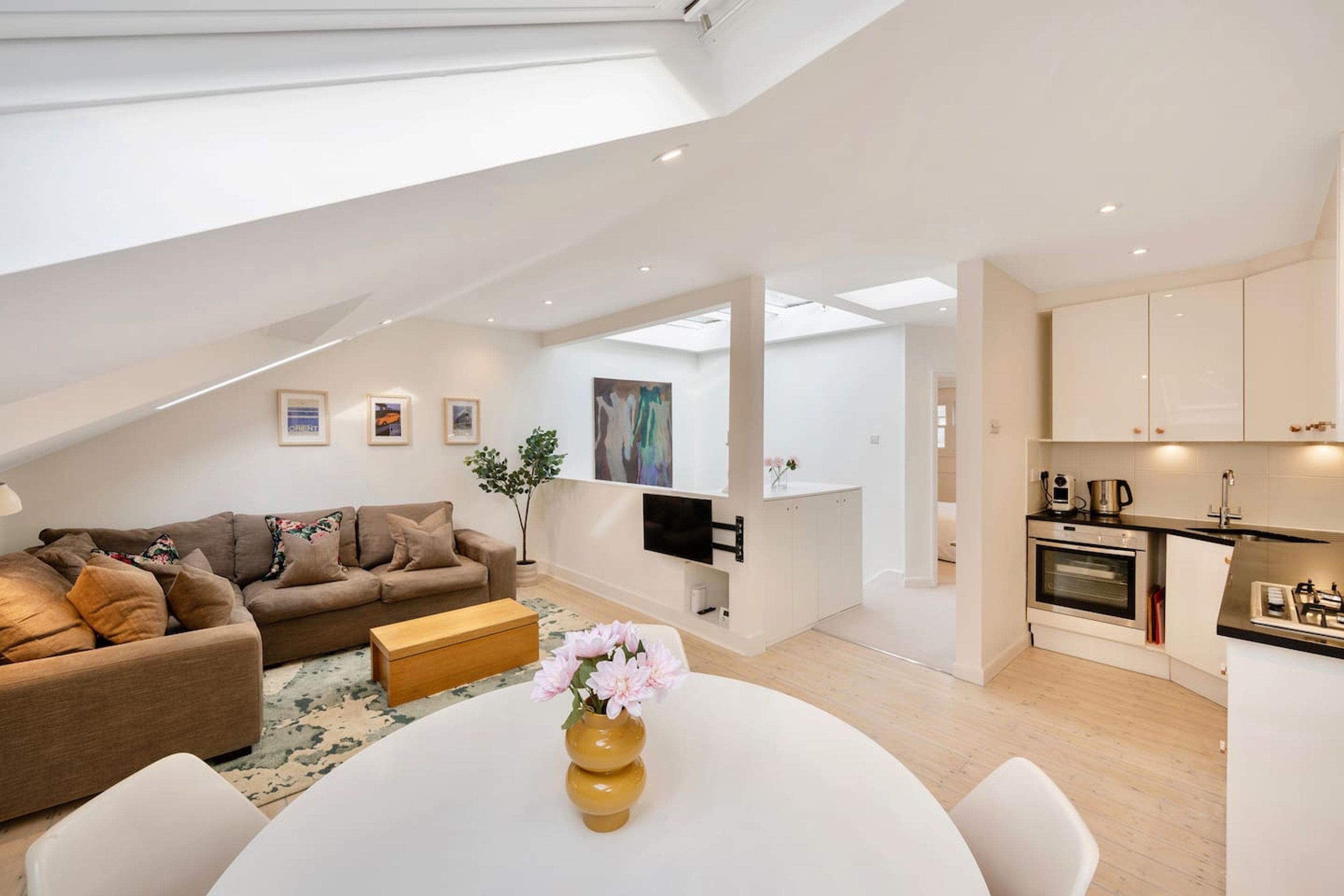 A modern apartment with a living room, dining area, kitchen, and a loft bedroom.