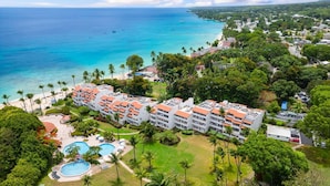 A resort with multiple buildings, a swimming pool, and a view of the ocean.