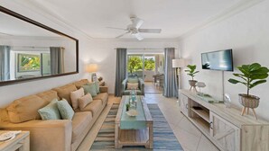 A living room with a sofa, coffee table, TV, and a balcony with outdoor furniture.
