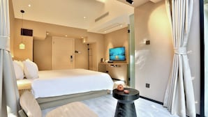 A modern hotel room with a large bed, a television, a small table, and a window with curtains. - Lotus Glade Hotel (Hangzhou)